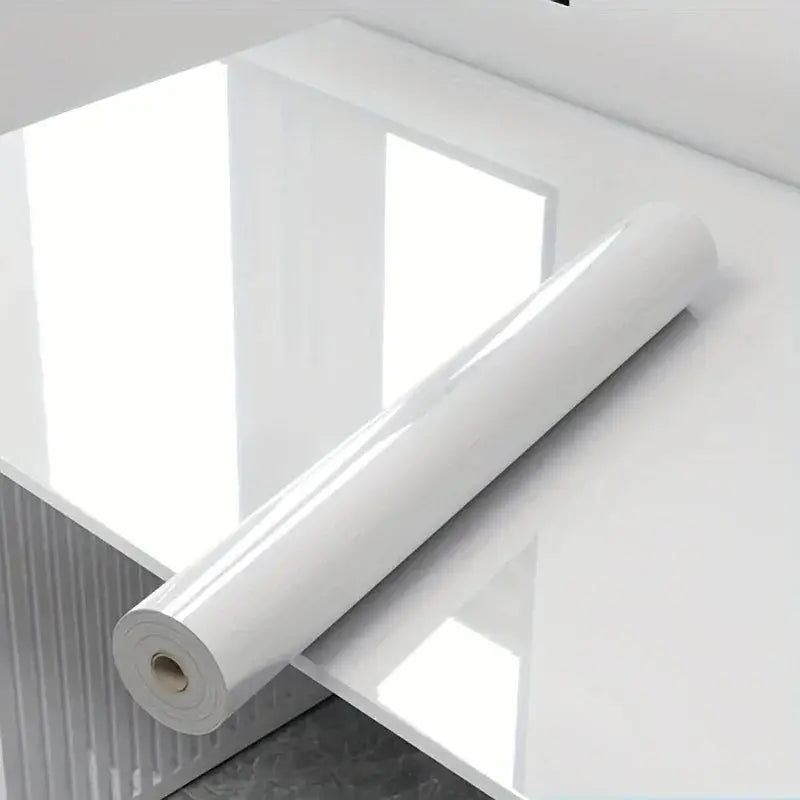 Eine sleek glossy weiße rolle selbstklebende marmor-klebefolie liegt auf spiegelnder oberfläche öl- und wasserdicht für küche und möbel