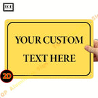 Personalisiertes 2d-wandschild aus aluminium in gelb mit schwarzer rahmen und individuell bedrucktem text