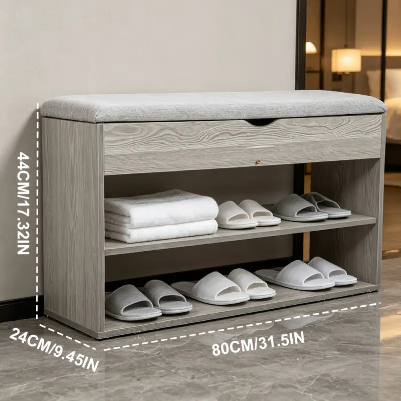Graues 3-stufiges schuhregal aus holz mit gepolsterter sitzfläche und zwei regalebenen mit weißen hausschuhen